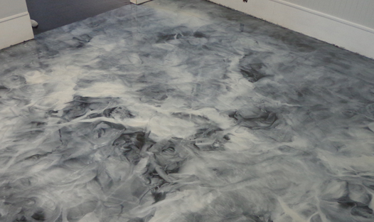 This image shows an living room with metallic epoxy floor. It has a combination of gray and white metallic epoxy.