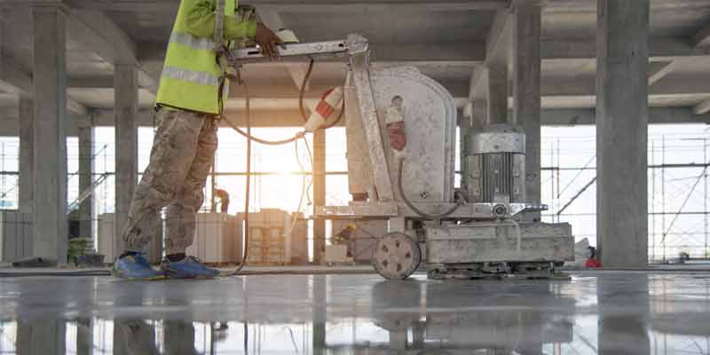 This image shows a man grinding the floor in preparation for coating.