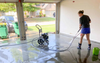 This image shows a man power spraying a garage floor.