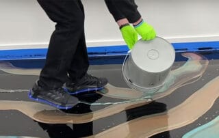 This image shows a man pouring brown epoxy paint on the floor.