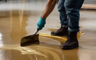 This image shows a man applying a yellow metallic epoxy on the floor.